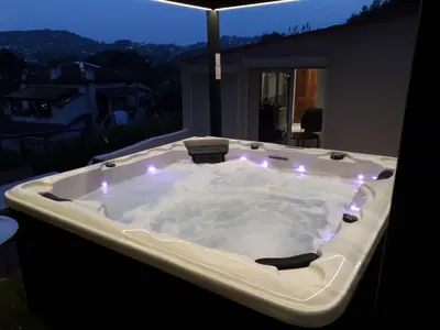 a jacuzzi tub with lights on a balcony at night at Piscine-Jacuzzi-Sauna -Videoprojecteur Perle Rare in Mougins