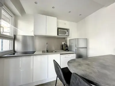a kitchen with white cabinets and a table at Superbe appartement avec terrasse centre-ville et plage à 5 min in Cannes