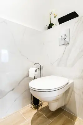 a white toilet in a bathroom with white marble walls at Elena YourHostHelper in Cannes