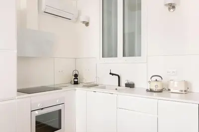 a white kitchen with white cabinets and a sink at 2chambres 2 salles de bains Palais des Festivals in Cannes