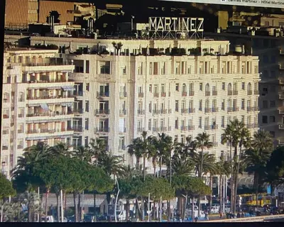 a large white building with palm trees in front of it at 2chambres 2 salles de bains Palais des Festivals in Cannes