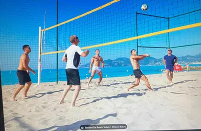 a group of men playing a game of volleyball on the beach at 2chambres 2 salles de bains Palais des Festivals in Cannes