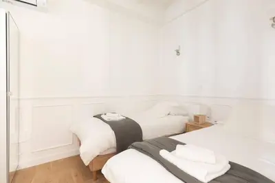 two beds in a bedroom with white walls and wood floors at 2chambres 2 salles de bains Palais des Festivals in Cannes
