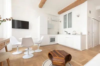 a white kitchen with white chairs and a table at 2chambres 2 salles de bains Palais des Festivals in Cannes