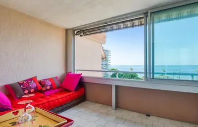 a living room with a red couch and a large window at Mer et Plage 2 étoiles in Cannes