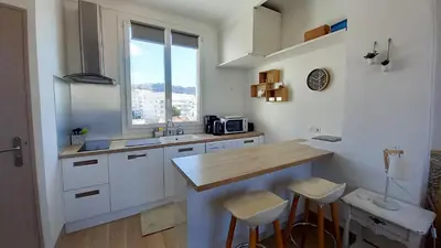 a kitchen with white cabinets and a counter with stools at Palais Gounod in Cannes