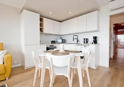 a kitchen with white cabinets and a table and chairs at Tulette in Cannes