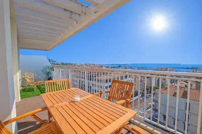 a deck with a wooden table and chairs on a balcony at Tulette in Cannes