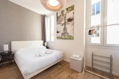 a bedroom with a white bed with a picture of the eiffel tower at Downtown Cannes walk to Beaches and Croisette in Cannes