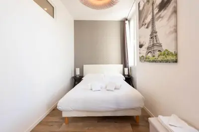 a bedroom with a white bed with a picture of the eiffel tower at Downtown Cannes walk to Beaches and Croisette in Cannes