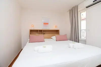 a bedroom with a large white bed with pink pillows at IMMOGROOM - Bright and Cosy - SUQUET - next to the beaches - AC in Cannes