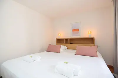 a bedroom with a white bed with pink pillows at IMMOGROOM - Bright and Cosy - SUQUET - next to the beaches - AC in Cannes
