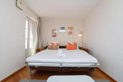 a bedroom with a bed with white sheets and orange pillows at IMMOGROOM - Bright and Cosy - SUQUET - next to the beaches - AC in Cannes