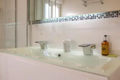 a white bathroom with a sink and a mirror at IMMOGROOM - Terrace with sea view - AC - Suquet - 5 min from the beach in Cannes
