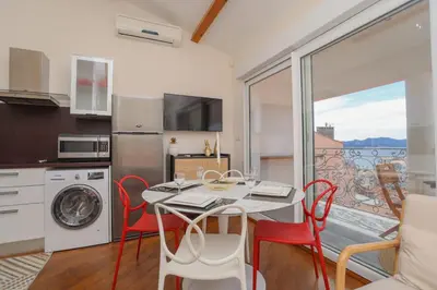 a kitchen with a table and chairs and a balcony at IMMOGROOM - Terrace with sea view - AC - Suquet - 5 min from the beach in Cannes