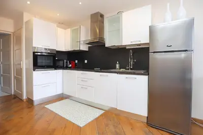 a kitchen with white cabinets and a stainless steel refrigerator at IMMOGROOM - Beautiful and Cosy - Air conditioner - 5 min from beaches in Cannes