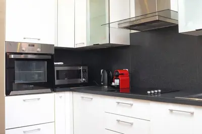 a kitchen with white cabinets and a black wall at IMMOGROOM - Beautiful and cosy- Suquet- near the beaches - AC in Cannes