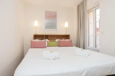 a bedroom with a large white bed with pink and green pillows at IMMOGROOM - Beautiful and cosy- Suquet- near the beaches - AC in Cannes