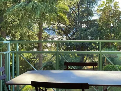 a table and chair on a balcony with trees at CANNES Appartement Duplex Piscine VUE Mer WIFI PARKING CLIM in Cannes