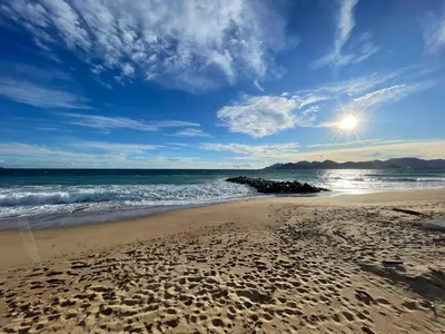 a beach with footprints in the sand and the ocean at CANNES Appartement Duplex Piscine VUE Mer WIFI PARKING CLIM in Cannes