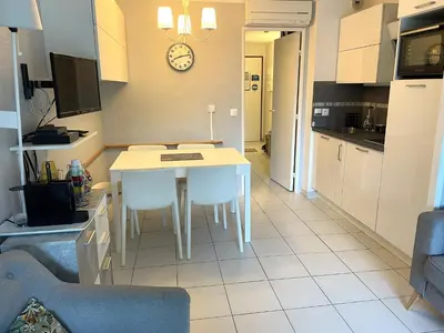 a kitchen with a table and a clock on the wall at CANNES Appartement Duplex Piscine VUE Mer WIFI PARKING CLIM in Cannes