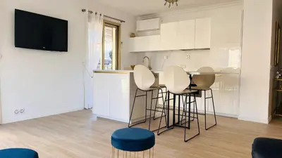 a kitchen with a bar with stools and a tv at le meilleur de Cannes au palm beach in Cannes