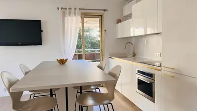 a kitchen with a table and chairs and a tv at le meilleur de Cannes au palm beach in Cannes