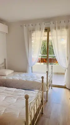 two beds in a bedroom with a large window at le meilleur de Cannes au palm beach in Cannes