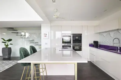 a white kitchen with a white counter and chairs at Cannes - Modern villa with 180° sea view in Vallauris