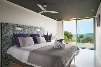a bedroom with a large bed with a ceiling fan at Cannes - Modern villa with 180° sea view in Vallauris