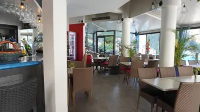 a restaurant with tables and chairs and a bar at Appartement 556, Vue Mer et piscine By Palmazur Vacances in Cannes