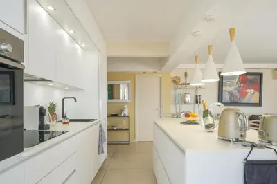 a kitchen with white counters and white appliances at Villa sur le toit - Vue mer exceptionnelle in Cannes
