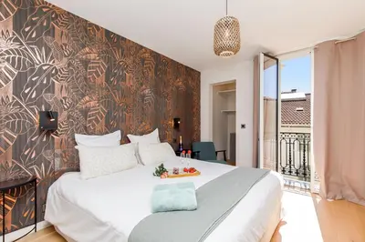a bedroom with a large white bed and a wall at 06AG - Bel appartement proche Palais des Festivals in Cannes