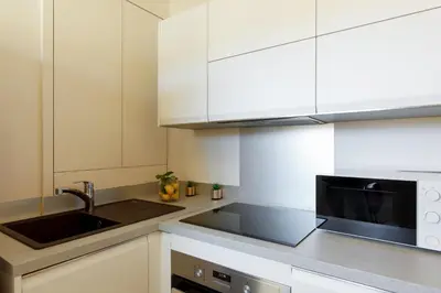 a kitchen with white cabinets and a sink and a microwave at 06AG - Bel appartement proche Palais des Festivals in Cannes