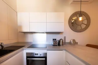 a kitchen with white cabinets and a clock on the wall at 06AG - Bel appartement proche Palais des Festivals in Cannes