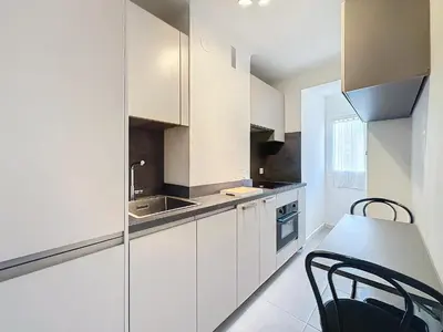 a kitchen with white cabinets and a table and chairs at 1 bedroom Latour Maubourg Cannes Riviera 245 in Cannes