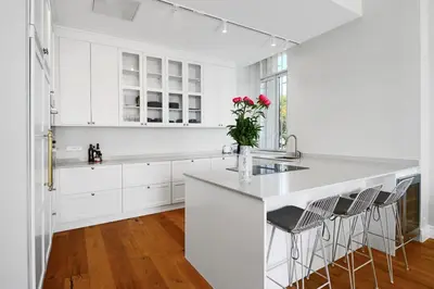 a white kitchen with white cabinets and a kitchen island with chairs at LE SUQUET - Bright renovated and spacious apartment in Cannes