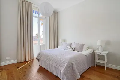 a white bedroom with a bed and a window at LE SUQUET - Bright renovated and spacious apartment in Cannes