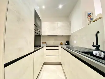 a kitchen with white cabinets and a black treadmill at Palais Azur By SCLS Locations in Cannes