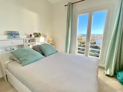 a bedroom with a white bed with a large window at Palais Azur By SCLS Locations in Cannes