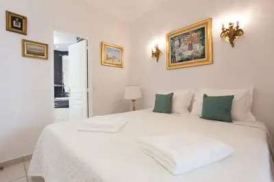 a white bedroom with a large white bed with green pillows at Cannes Meynadier: Superbe appartement trois pièces in Cannes