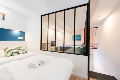 a bedroom with a white bed with a large window at LE CHANCEUX fabuleux duplex en design, pour loisir en couple ou congrès in Cannes