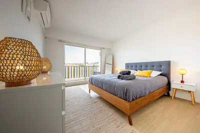 a bedroom with a bed and a large window at Cannes au Calme à 10 mn à pieds du centre, aperçue mer - Parking gratuit in Cannes