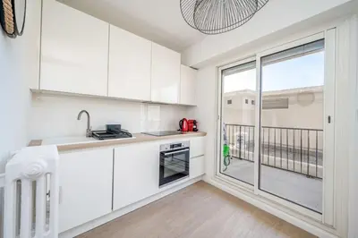 a kitchen with white cabinets and a large window at Cannes au Calme à 10 mn à pieds du centre, aperçue mer - Parking gratuit in Cannes