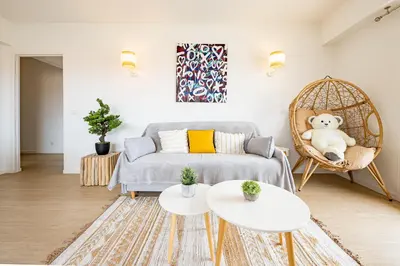 a living room with a bed and a rattan chair at Cannes au Calme à 10 mn à pieds du centre, aperçue mer - Parking gratuit in Cannes