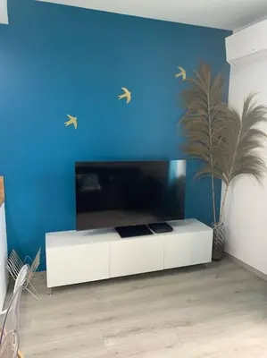 a living room with a blue wall and a white cabinet at Appartement Etat neuf La Chantalane -proche centre-ville in Cannes