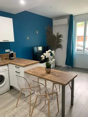 a kitchen with a table and chairs and a blue wall at Appartement Etat neuf La Chantalane -proche centre-ville in Cannes