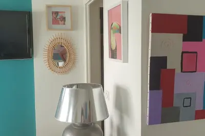 a lamp in a room with a mirror and paintings at Centre et plage tout à pied échappée mer in Cannes