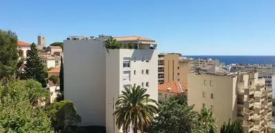 a white building with a palm tree on top of it at Centre et plage tout à pied échappée mer in Cannes