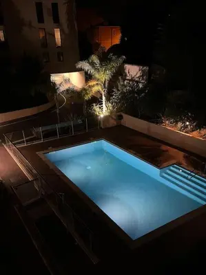 a large swimming pool at night in a backyard at 2 pièces avec clim, terrasse, piscine, 100m plage in Cannes